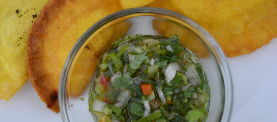 Colombian aji sauce in a container surrounded by empanadas