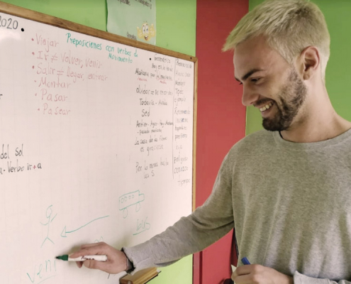 Student in front of a white board practicing writing in Spanish