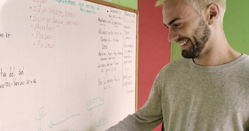 Student in front of a white board practicing writing in Spanish