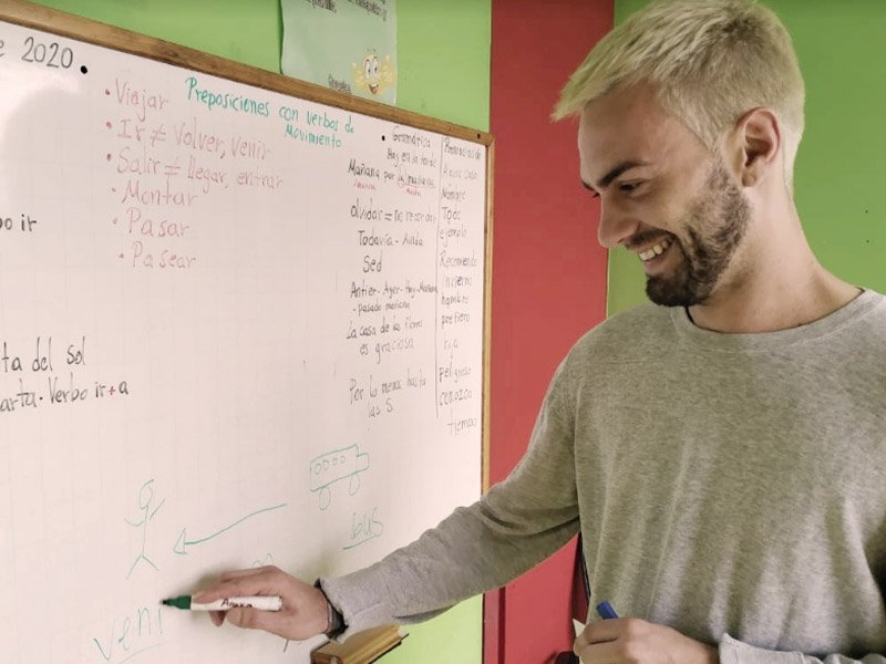 Student in front of a white board practicing writing in Spanish