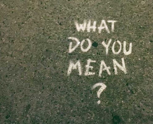 Street sign with the words what do you mean? in reference to the Colombian word "vaina"